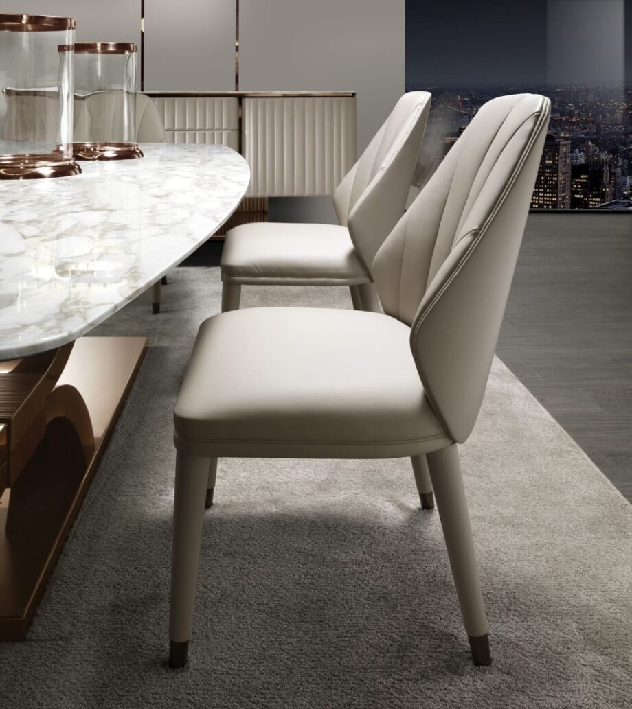 Elite chair | DV home. Luxurious swivel armchair with quilted back and polished stainless steel base, blending Art Deco elegance with contemporary comfort.