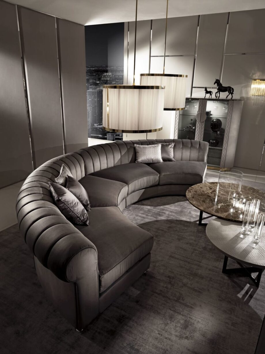 Kent Round sofa | DV home. Luxurious curved sectional sofa with goose feather cushions and chrome base, embodying Art Deco elegance.