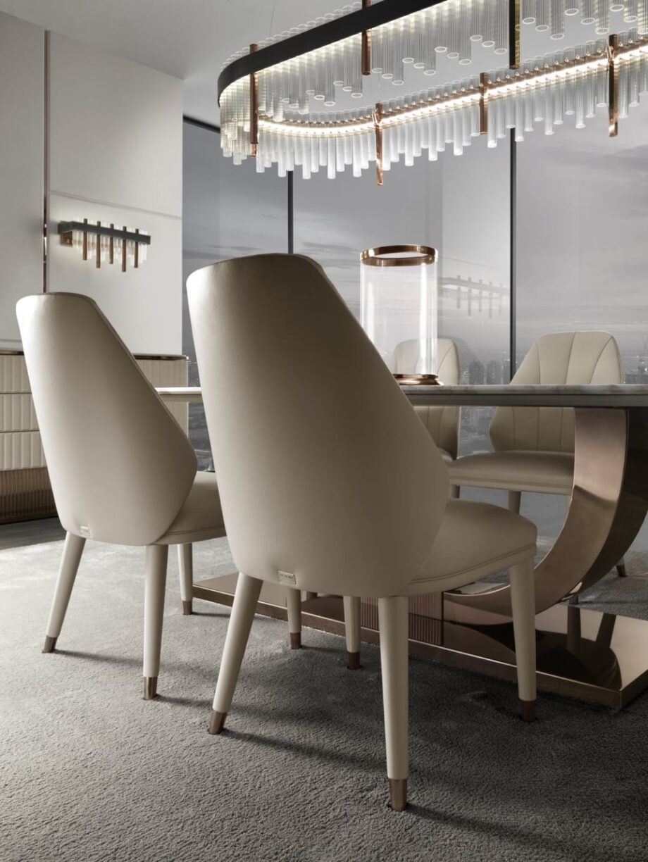 Elite chair | DV home. Luxurious swivel armchair with quilted back and polished stainless steel base, blending Art Deco elegance with contemporary comfort.