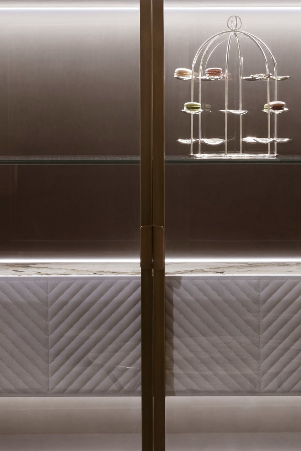 Iole sideboard | Rugiano. Luxurious sideboard with leather upholstery, bronze details, marble top with backlighting, and elegant glass doors.