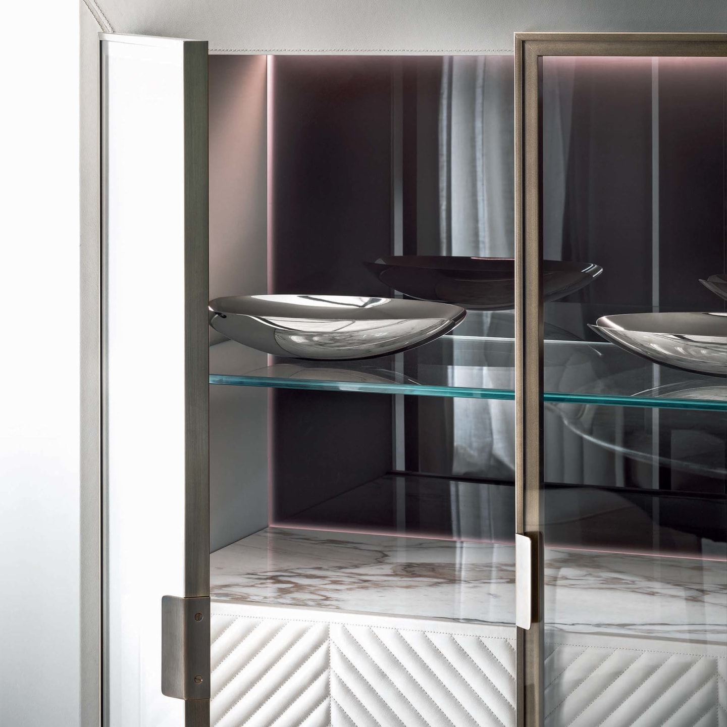 Iole sideboard | Rugiano. Luxurious sideboard with leather upholstery, bronze details, marble top with backlighting, and elegant glass doors.